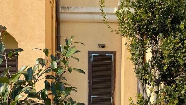 A building entrance with a closed door, a pathway, and surrounding greenery. - Roma 1 Apartment - THE V Collection (Turate)