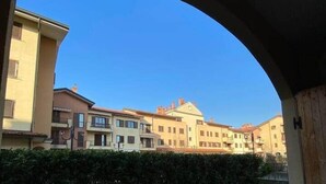 Une cour donnant sur des immeubles à plusieurs étages, avec une haie et une porte en bois.