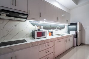 Une cuisine moderne équipée d’un four à micro-ondes encastré, d’une bouilloire et d’un réfrigérateur.