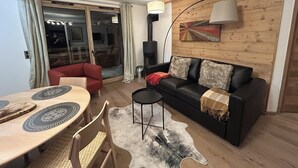 A modern living room with a black leather sofa, a dining table with a unique circular design, and a large wooden wall with a colorful abstract painting. - Quartz 404 by Avecoeur (Huez)