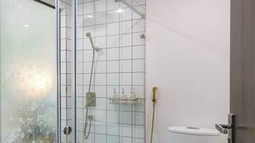 A modern bathroom with a glass shower enclosure, a toilet, and a tiled floor.