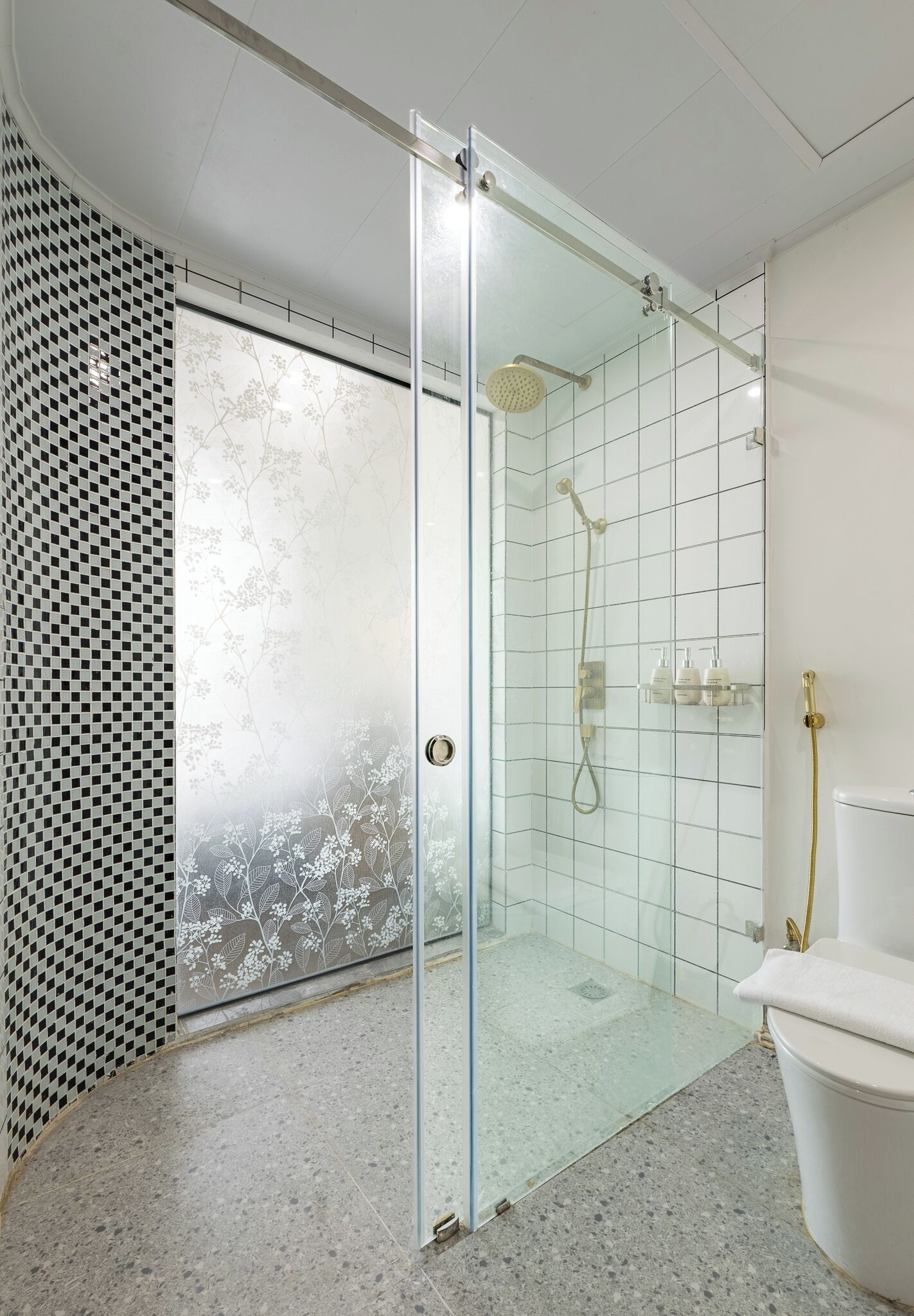 A modern bathroom with a glass-enclosed shower, a toilet, and a tiled floor.
