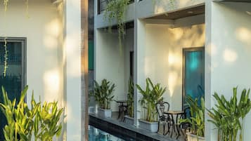 A multi-level building with a swimming pool, outdoor seating, and potted plants.