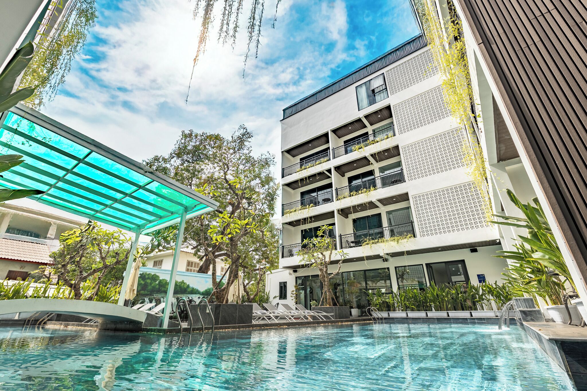 A modern building with a pool, outdoor seating, and a covered area.