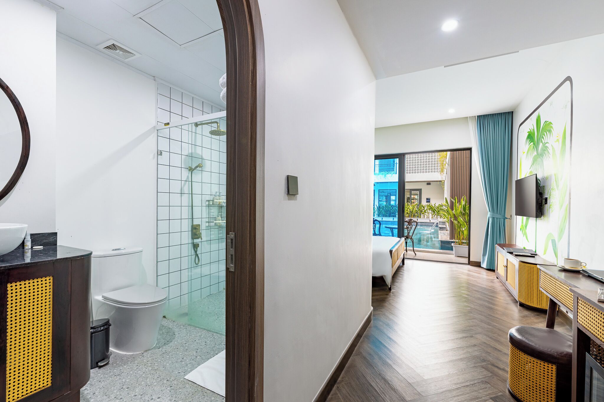 A modern hotel bathroom with a glass shower, a toilet, and a sink.