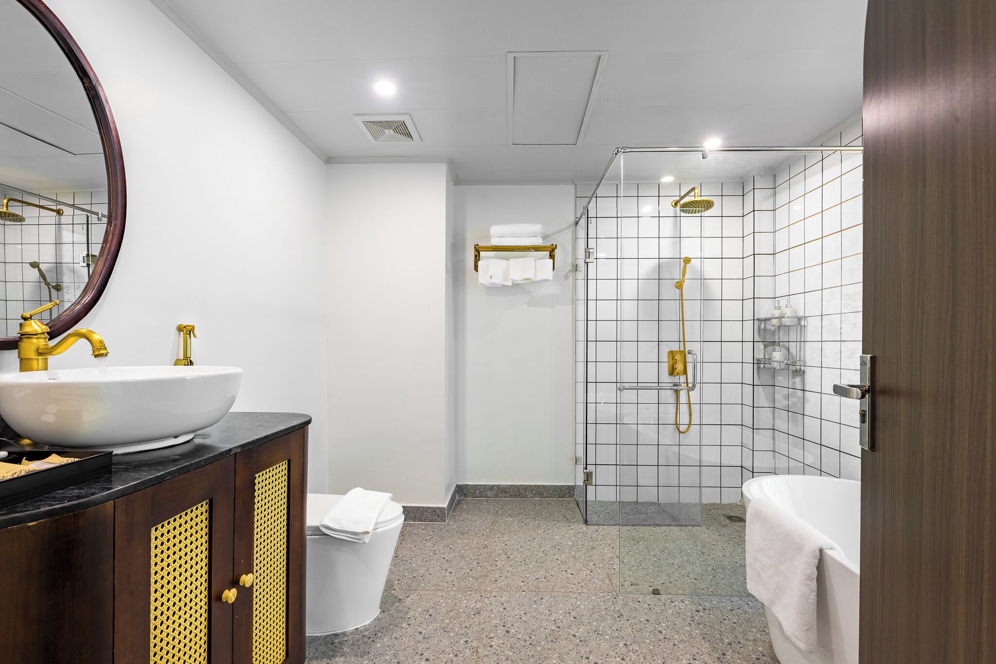 A modern bathroom with a white sink, gold fixtures, and a glass-enclosed shower area.