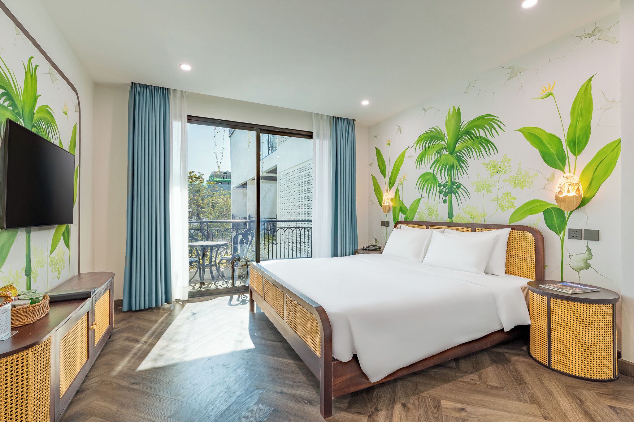Ein modernes Hotelzimmer mit einem großen Bett, einem Flachbildfernseher, einem Balkon mit Aussicht und einer Wandmalerei mit Pflanzenmotiven.