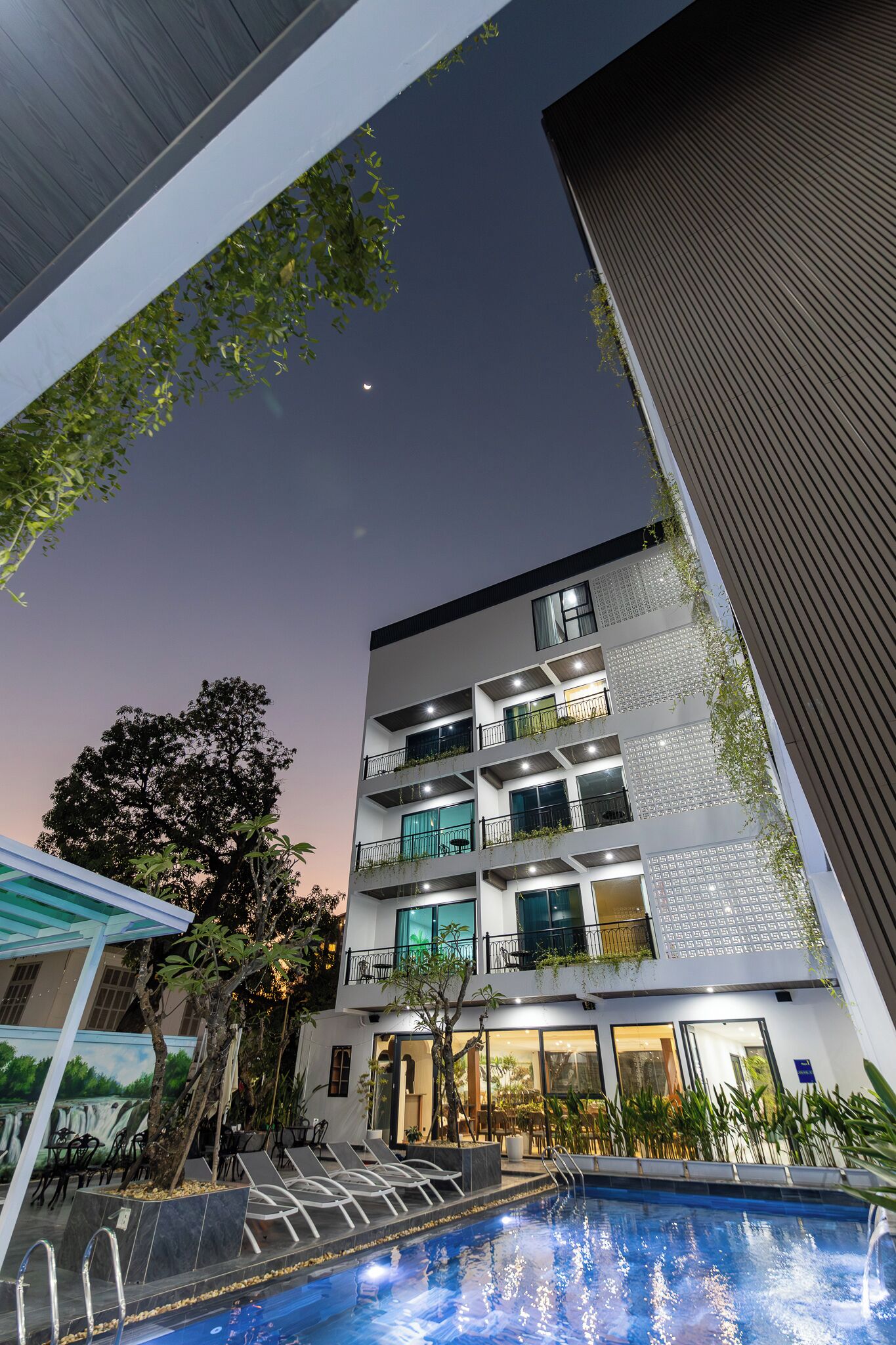 A modern building with multiple floors, outdoor pool, and surrounding greenery.