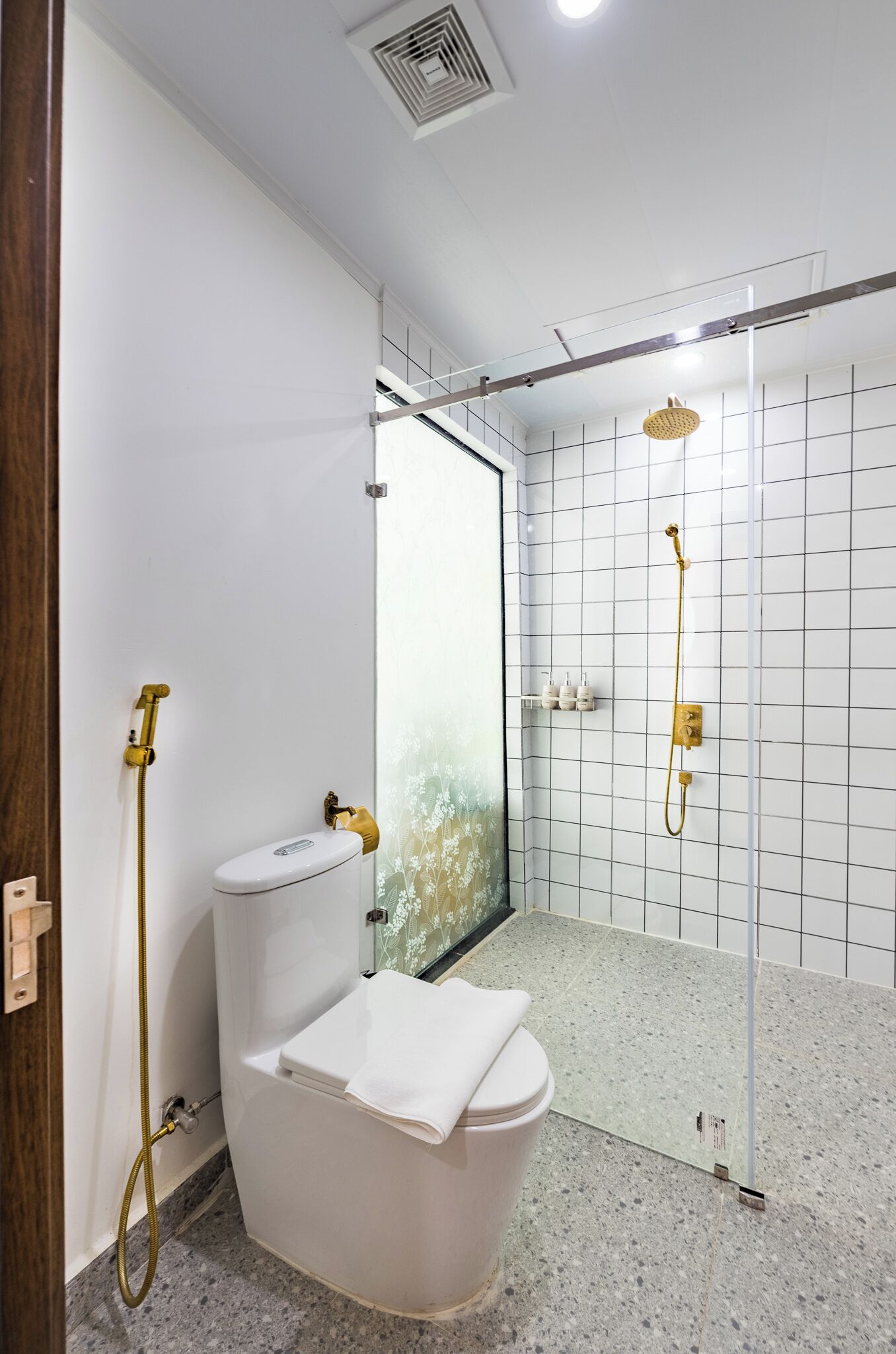 A bathroom with a toilet, a shower, and a glass-enclosed shower area.
