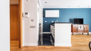 A modern kitchen with a marble backsplash, wooden cabinets, and a built-in island. - 1 bedroom apartment with parking in Eixample (Barcelona)