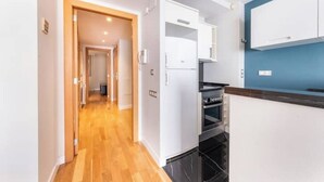 A modern kitchen with white cabinets, a black oven, and a wooden floor. - 1 bedroom apartment with parking in Eixample (Barcelona)