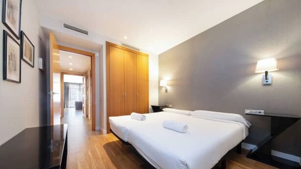A hotel room with a large bed, a desk, and a wardrobe. - 1 bedroom apartment with parking in Eixample (Barcelona)