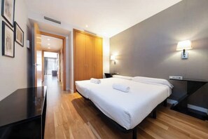 A hotel room with a large bed, a desk, and a wardrobe. - Cozy one-bedroom apartment in the Eixample with parking (Barcelona)