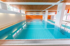 Una piscina con suelo de baldosas y techo de madera.