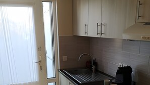 A kitchen with white cabinets, a black countertop, a sink, and a coffee maker. - La Perle de l'Océan – Pool and Terrace (Guidel)