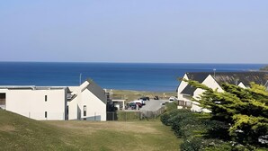 A coastal residential area with houses, a parking lot, and a view of the sea. - La Perle de l'Océan – Pool and Terrace (Guidel)