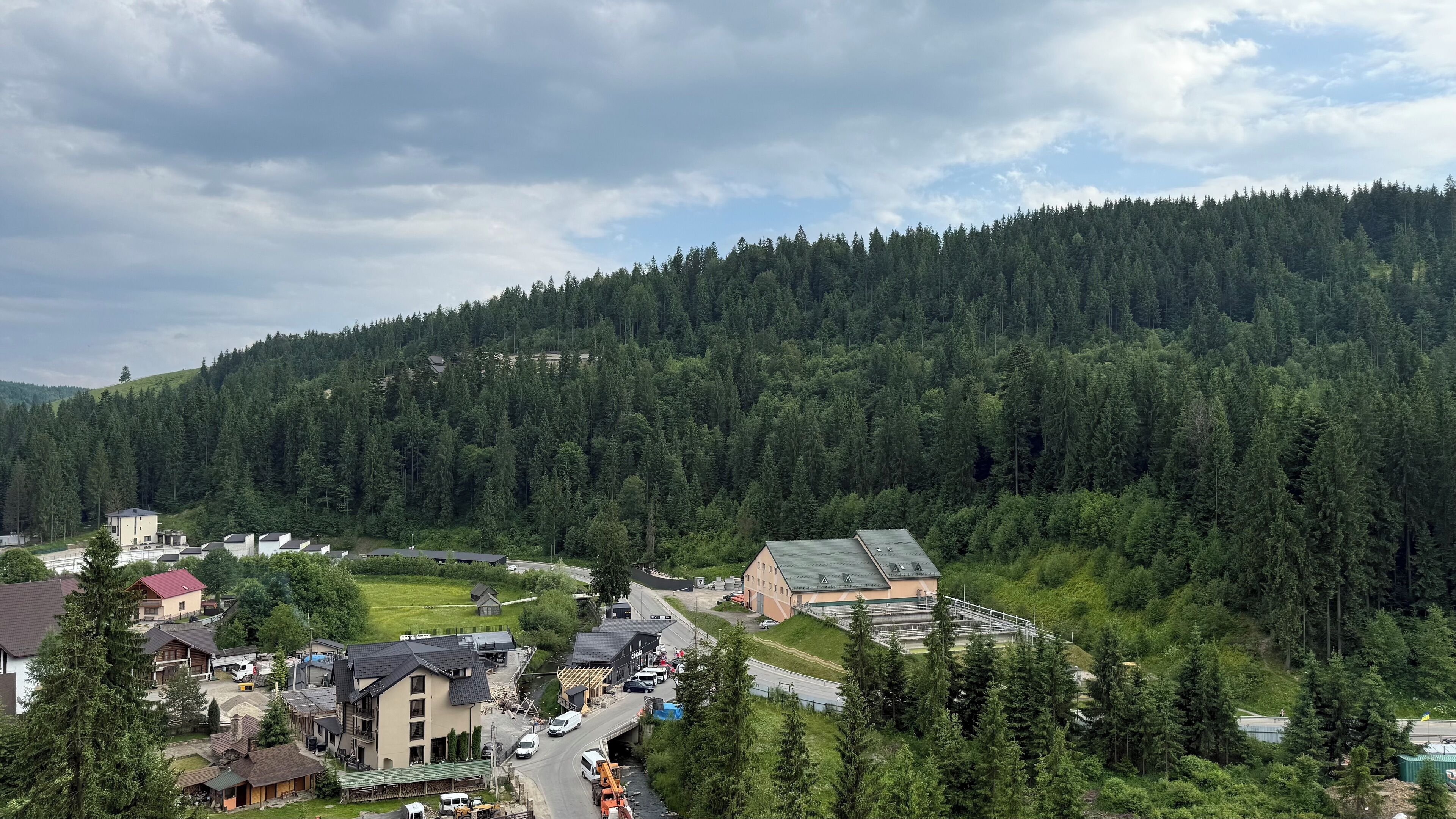 Un quartier résidentiel avec des maisons, une route et une colline boisée en arrière-plan.
