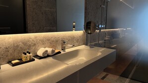 Une salle de bain moderne avec un grand lavabo, un miroir et une douche.