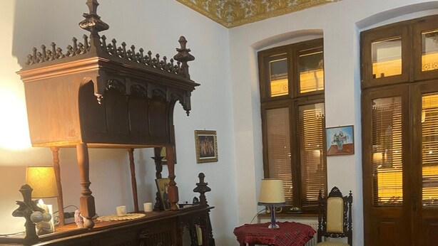 Een klassieke kamer met een houten dressoir, een rode bed, een bankje en een kamerbreed tapijt met dessin.