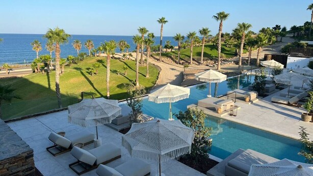 A pool area with lounge chairs and umbrellas, surrounded by palm trees and a view of the ocean. - Amazing Sea views # Macenas Resort # 2BR # Sunbeds (Mojácar)