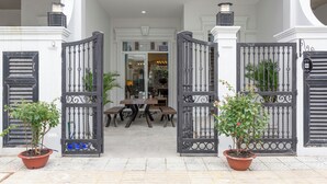 A gated entrance with a table and chairs, potted plants, and a clear view into the building. - L'amour Villa with Sauna at City Center (Da Nang)