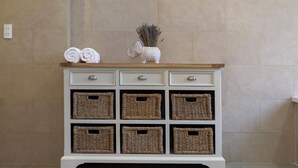 A white console table with six wicker baskets and a decorative elephant vase. - L'amour Villa with Sauna at City Center (Da Nang)