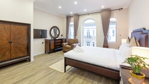 A modern hotel room with a large bed, a wooden wardrobe, a television, a desk with a lamp, and a potted plant. - L'amour Villa with Sauna at City Center (Da Nang)