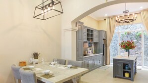 A dining area with a table set for four, grey chairs, and a chandelier. - L'amour Villa with Sauna at City Center (Da Nang)