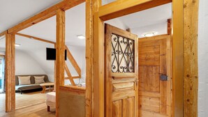 Un intérieur en bois comprenant un canapé, une table et une porte ornée d’un motif décoratif en métal.