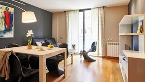Un espai de viure modern amb zona de menjador, sofà i prestatgeria.