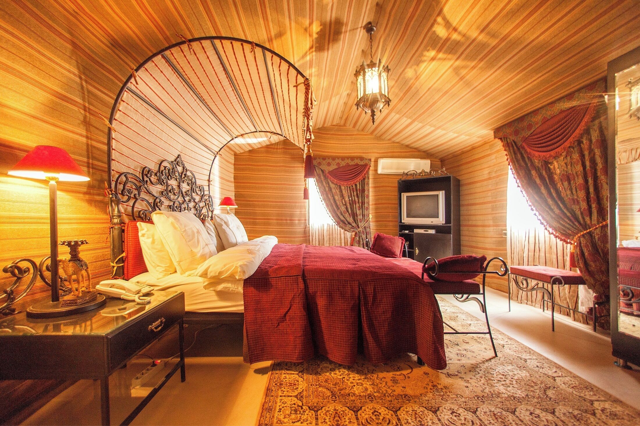 A room with a bed, a desk, a chair, a television, and a decorative fan.