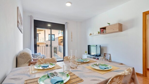 A dining area with a table set for four, a television, and a view to the outside. - Apartment 'Ángel' with Private Terrace, Wi-Fi and Air Conditioning (Vinebre)