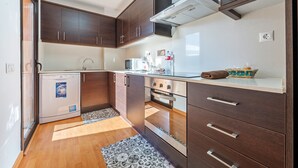A compact kitchen with dark wooden cabinets, a built-in oven, and a dishwasher. - Apartment 'Ángel' with Private Terrace, Wi-Fi and Air Conditioning (Vinebre)