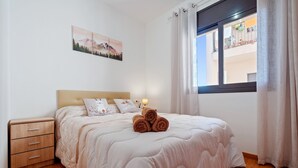 A bedroom with a bed, a nightstand, a window with curtains, and a wall-mounted picture. - Apartment 'Ángel' with Private Terrace, Wi-Fi and Air Conditioning (Vinebre)