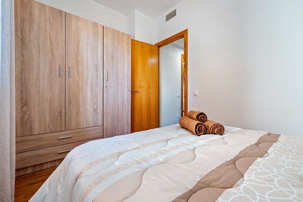 Un dormitorio con cama, un armario de madera y una puerta que da a otra habitación.