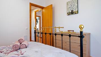 A bedroom with a bed, a wooden dresser, a mirror, and a painting on the wall.