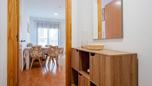 A hallway with a wooden cabinet, a dining area with a table and chairs, and a window with curtains. - Apartment 'Ángel' with Private Terrace, Wi-Fi and Air Conditioning (Vinebre)