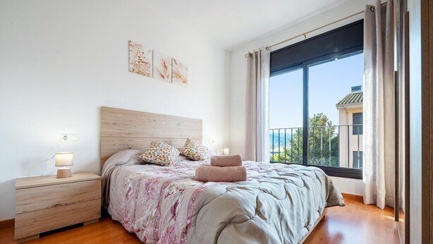 A bedroom with a large bed, wooden headboard, bedside tables, and a window with a view.