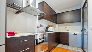 A compact kitchen with dark wooden cabinets, a white countertop, and a built-in oven.