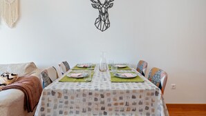 A dining area with a table set for four, a macrame wall hanging, and a geometric wall art piece.