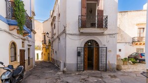 A narrow street with a building featuring a balcony, a gate, and a parked scooter. - Apartment 'Gabriele  Salento' with Private Terrace, Wi-Fi and Air Conditioning (Gallipoli)