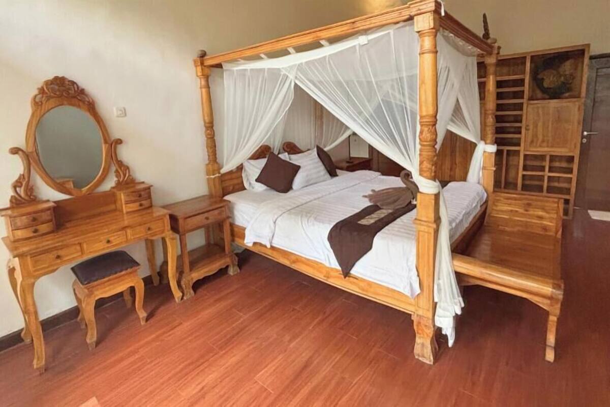 A four-poster bed with a canopy, wooden nightstands, a mirror, and a wardrobe.