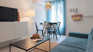Una sala de estar moderna con un televisor de pantalla plana, una mesa de comedor con sillas, un sofá y una cesta colgante.