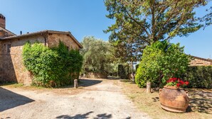 Un bâtiment rustique en pierre, avec une allée de gravier menant à un portail en bois.