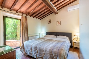 Un dormitorio con cama, ventana con cortinas, radiador y aire acondicionado de pared.
