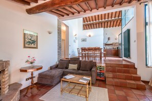 A living room with a sofa, a coffee table, a fireplace, and a staircase leading to a kitchen. - Villa Capannina with Private Pool, Wi-Fi and Air Conditioning (Vico dʼArbia)