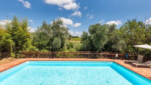 Ein rechteckiger Pool mit Holzterrasse und Holzzaun.
