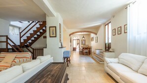 Ein großzügiger Wohnbereich mit Treppe, Essbereich und einer Couch.