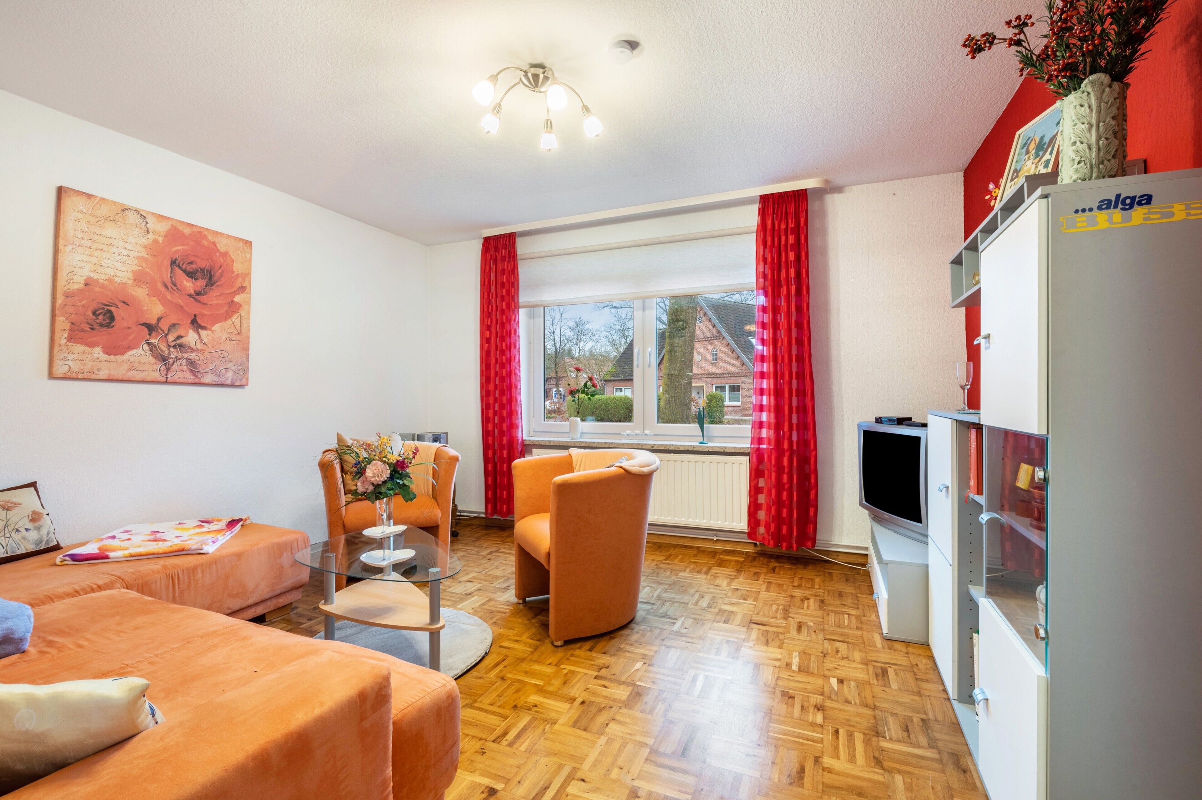 A living room with a sofa, armchair, and a small table with a vase.