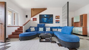A living room with a sectional sofa, a coffee table, a staircase, and a kitchen area. - Villa 'La Dimora di Patty' with Sea View, Wi-Fi and Air Conditioning (San Cataldo)